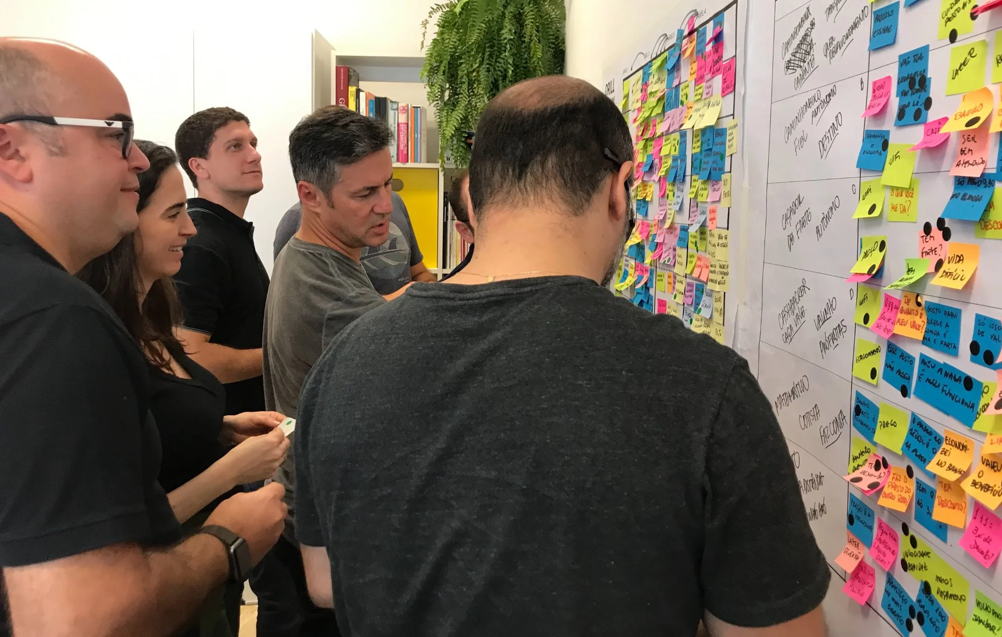 Equipe votando e priorizando na parede de post-its